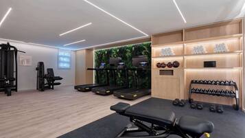 A modern gym with treadmills, weight machines, and a bench.