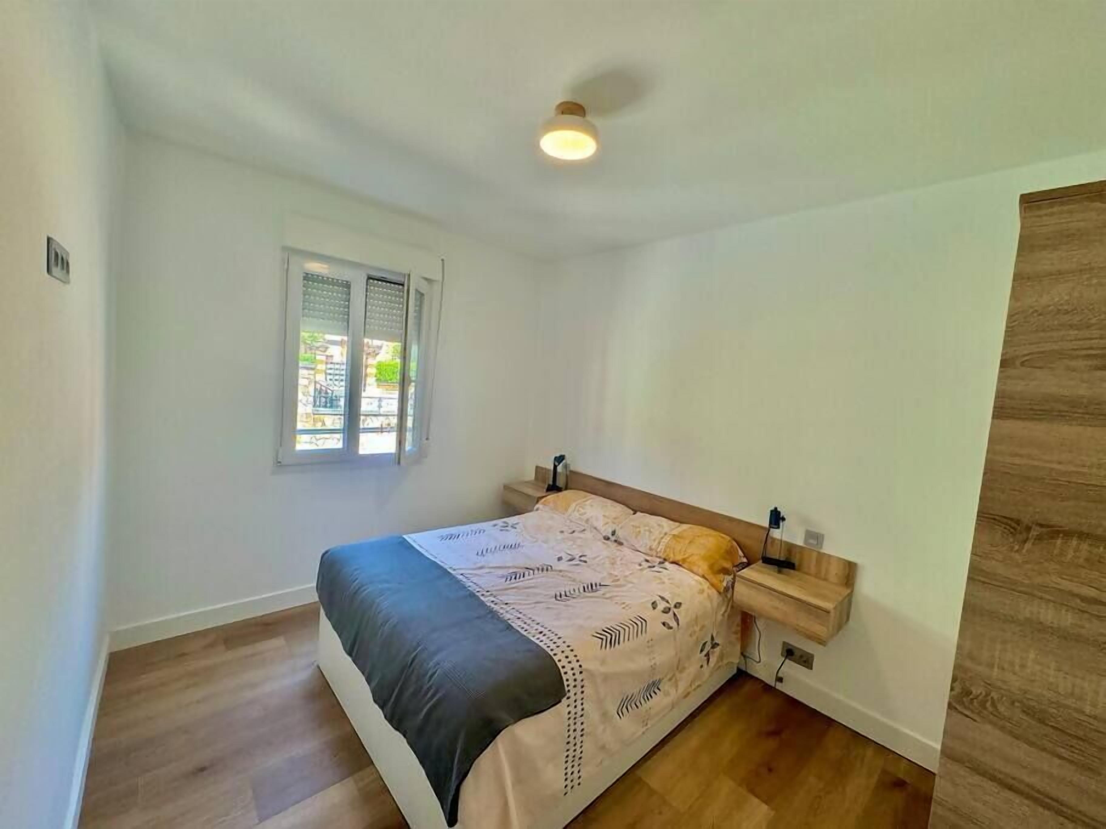 Una camera da letto con un letto, comodini, una finestra e una luce a soffitto.