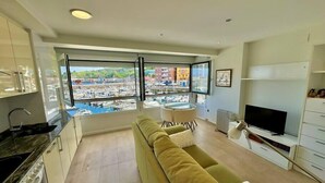 A modern living room with a sofa, TV, and dining area. A large window offers a view of a marina. - Kai begi, wonderful views of the port. (Bermeo)