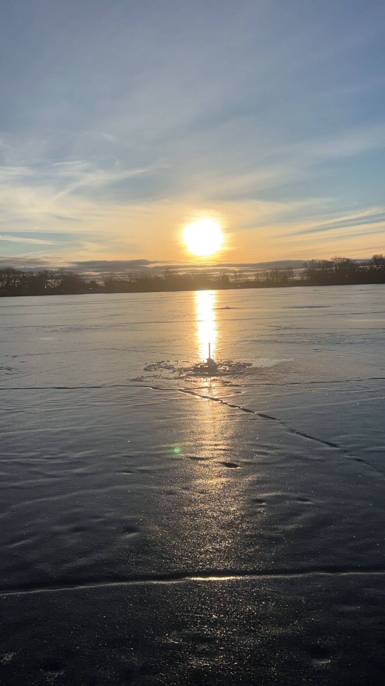 Un lago ghiacciato con il sole che si riflette sulla superficie.