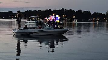 Un bote amarrado en un lago tranquilo con un speedboat amarrado y una persona de pie en el muelle.