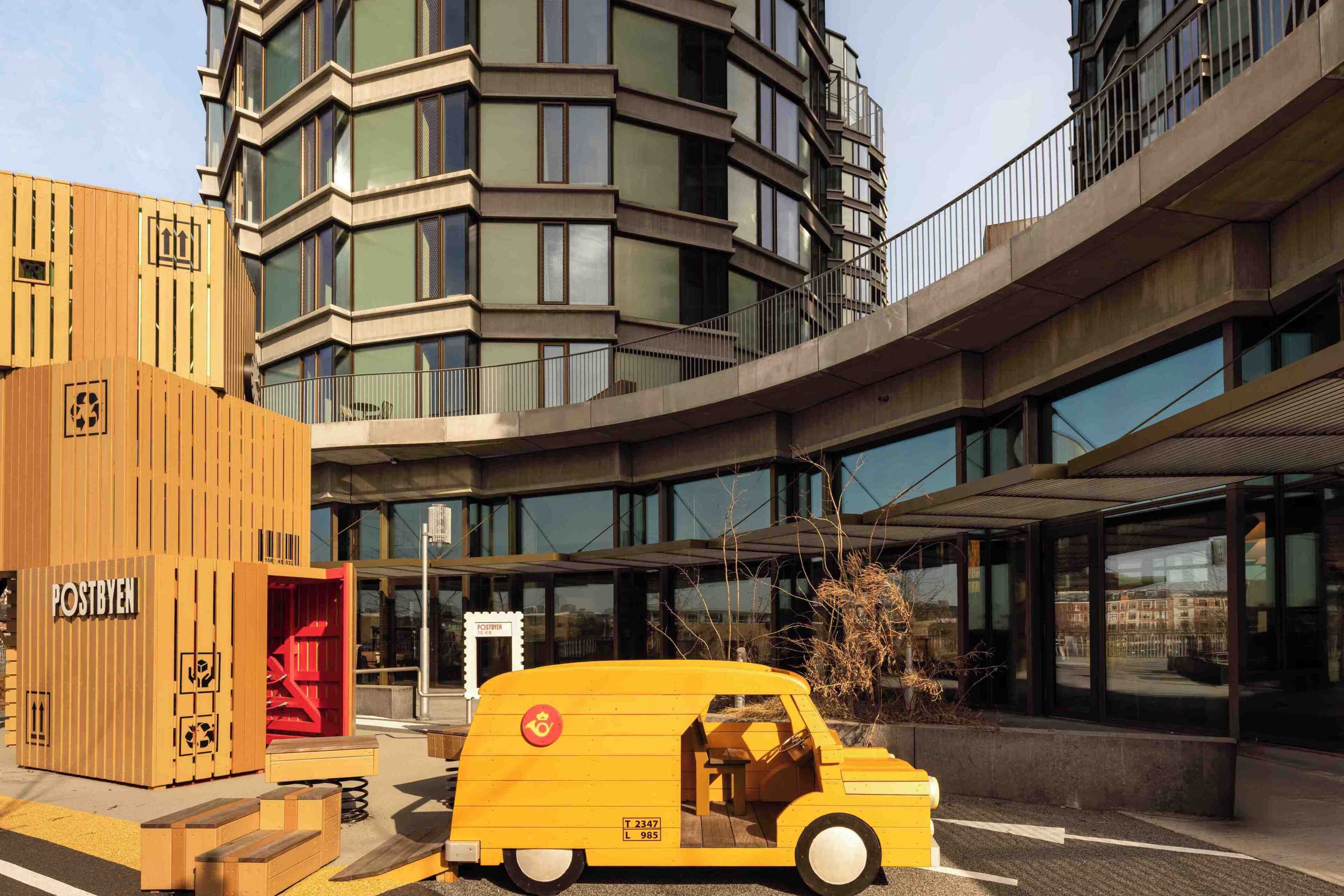 Een modern gebouw met een geel voertuig ervoor geparkeerd.