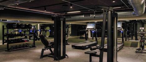 A gym with weightlifting equipment, treadmills, and a mirrored wall.