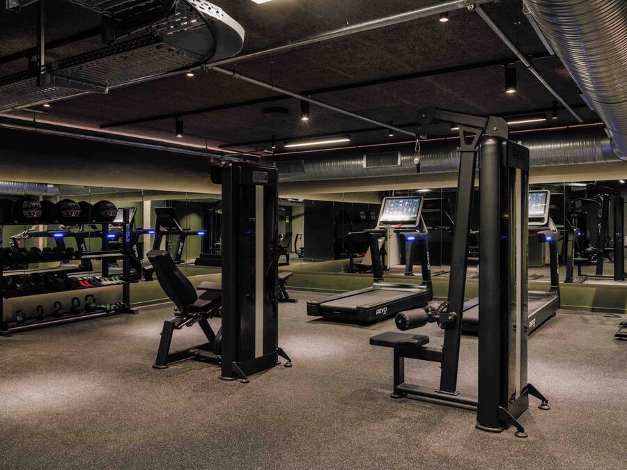 A gym with weightlifting equipment, treadmills, and a mirrored wall.