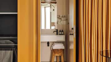 A bathroom with a white sink, mirror, and wooden stool.