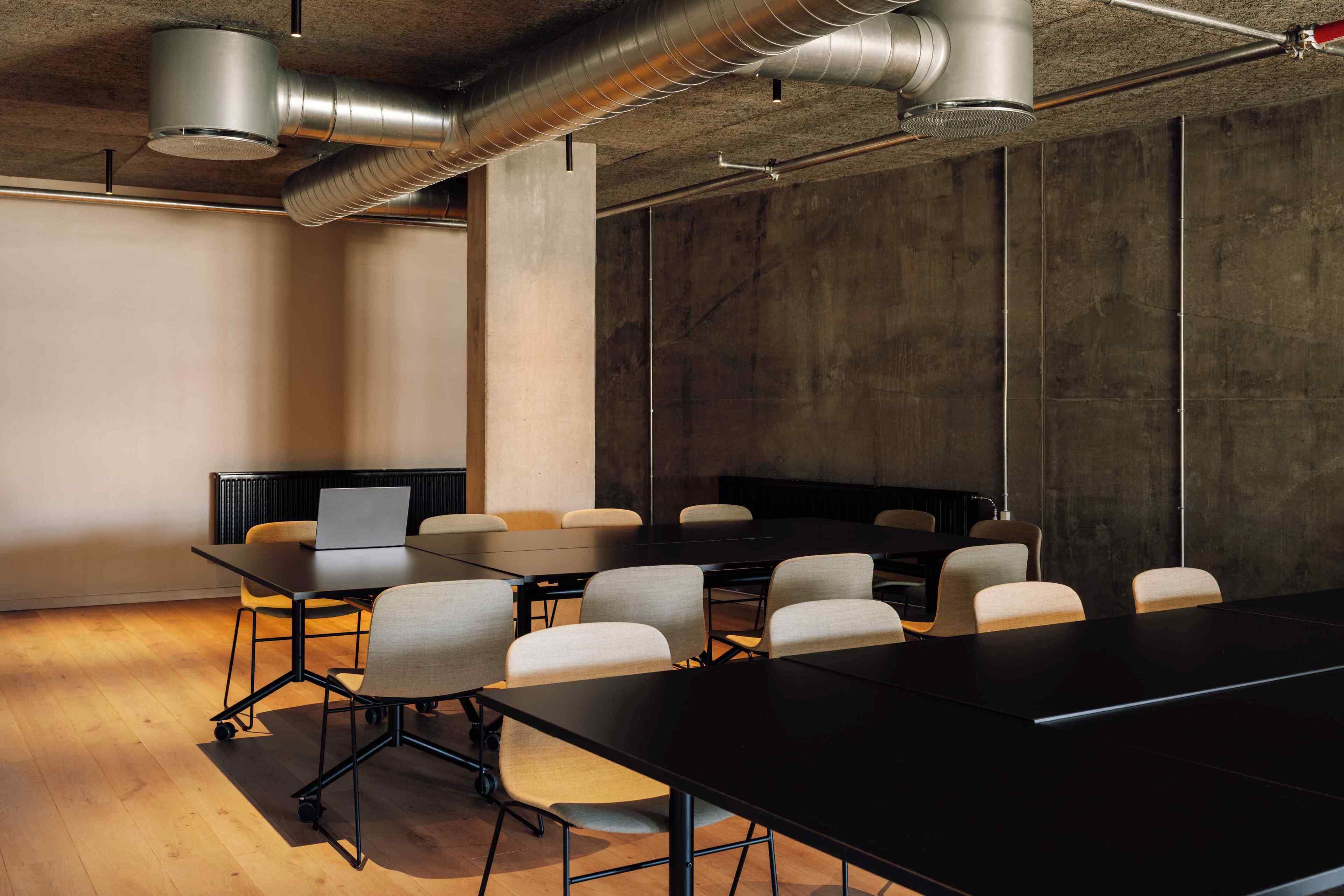 A conference room with a long table, chairs, and a laptop on a table.
