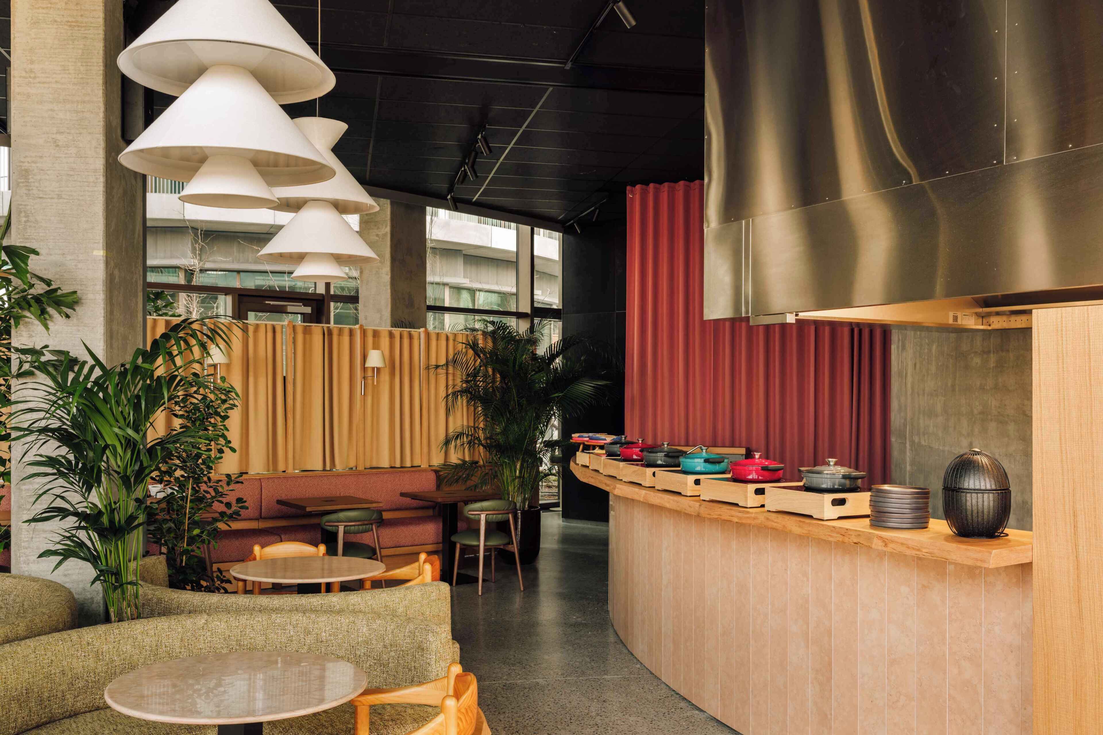 A modern interior with a curved wooden counter, seating areas, and hanging pendant lights.