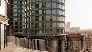 Un edificio moderno con fachada curva, múltiples ventanas y un paseo peatonal.
