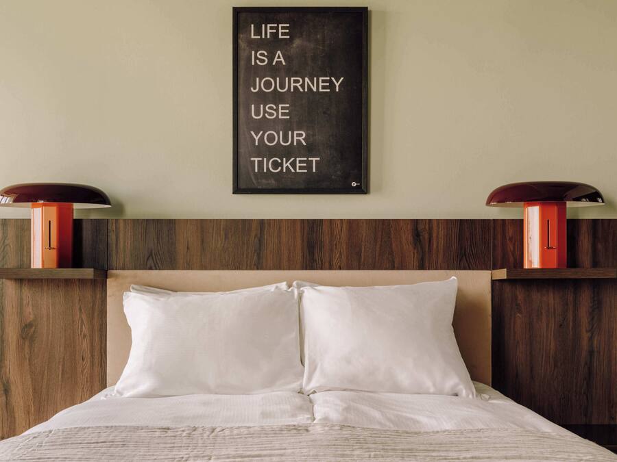 Un lit bien fait, avec du linge de lit blanc et une tête de lit en bois.