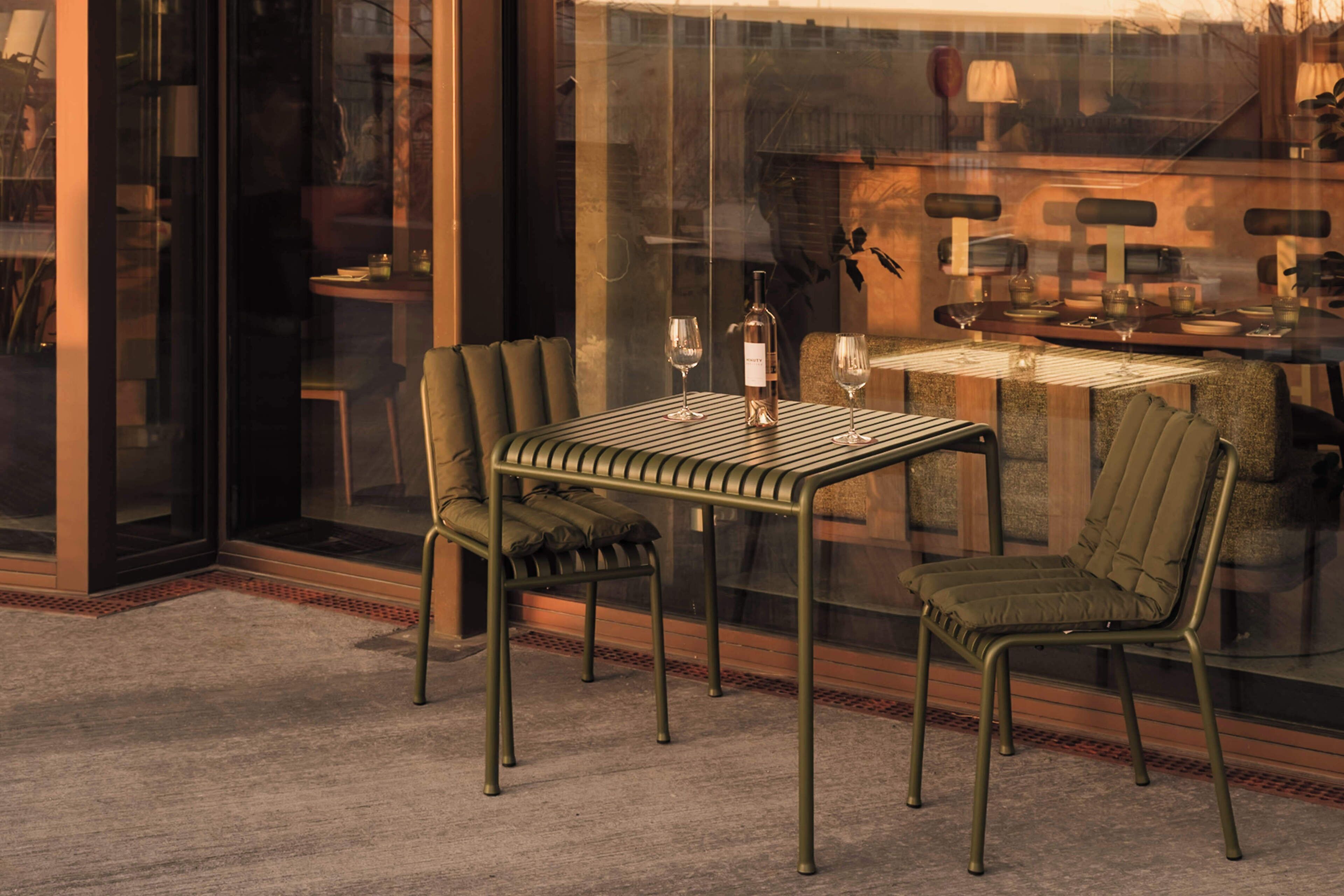 A dining area with a table and chairs, a bottle of wine, and a glass on the table.