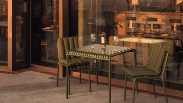 A dining area with a table and chairs, a bottle of wine, and a glass on the table.