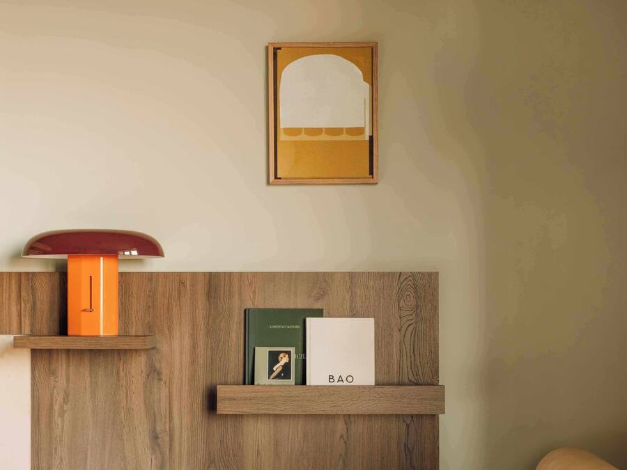 Een houten wand met een plank waarop boeken en een lijst staan.