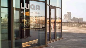A modern building with large glass windows and a sign reading 'LUQA'.