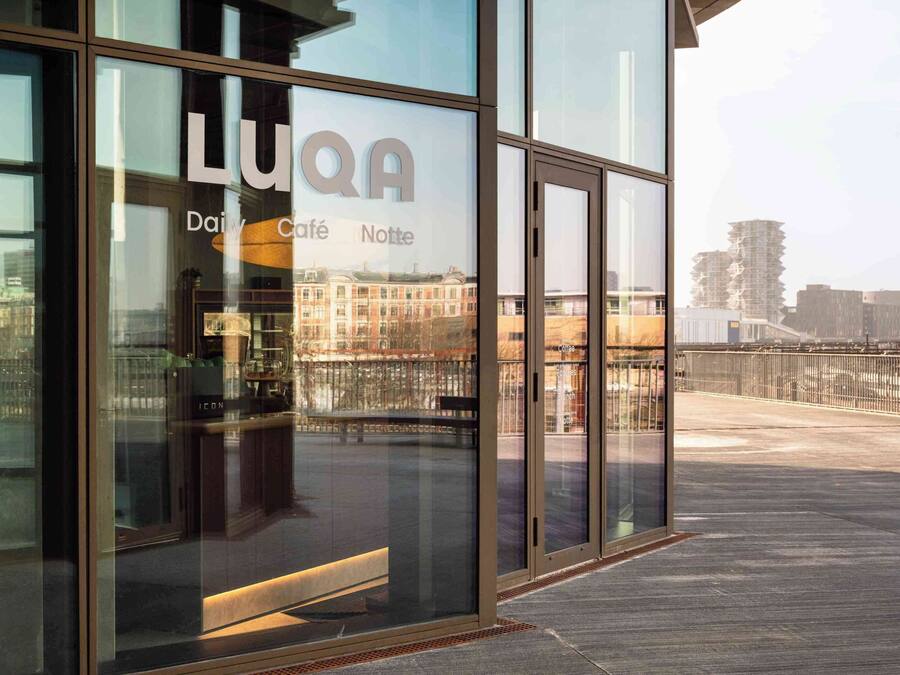 Moderni rakennus, jossa on suuret lasi-ikkunat ja kyltti, jossa lukee »LUQA».