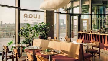 A modern cafe with large windows, seating arrangements, and a bar area.