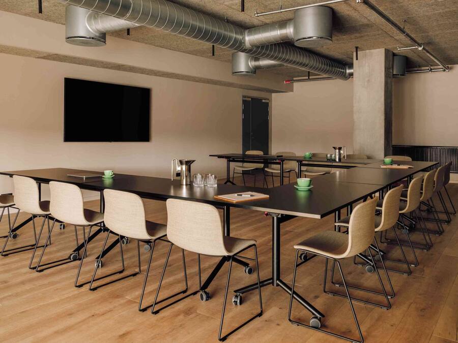 Une salle de conférence équipée d’une longue table, de chaises, d’un écran de projection et d’un radiateur.