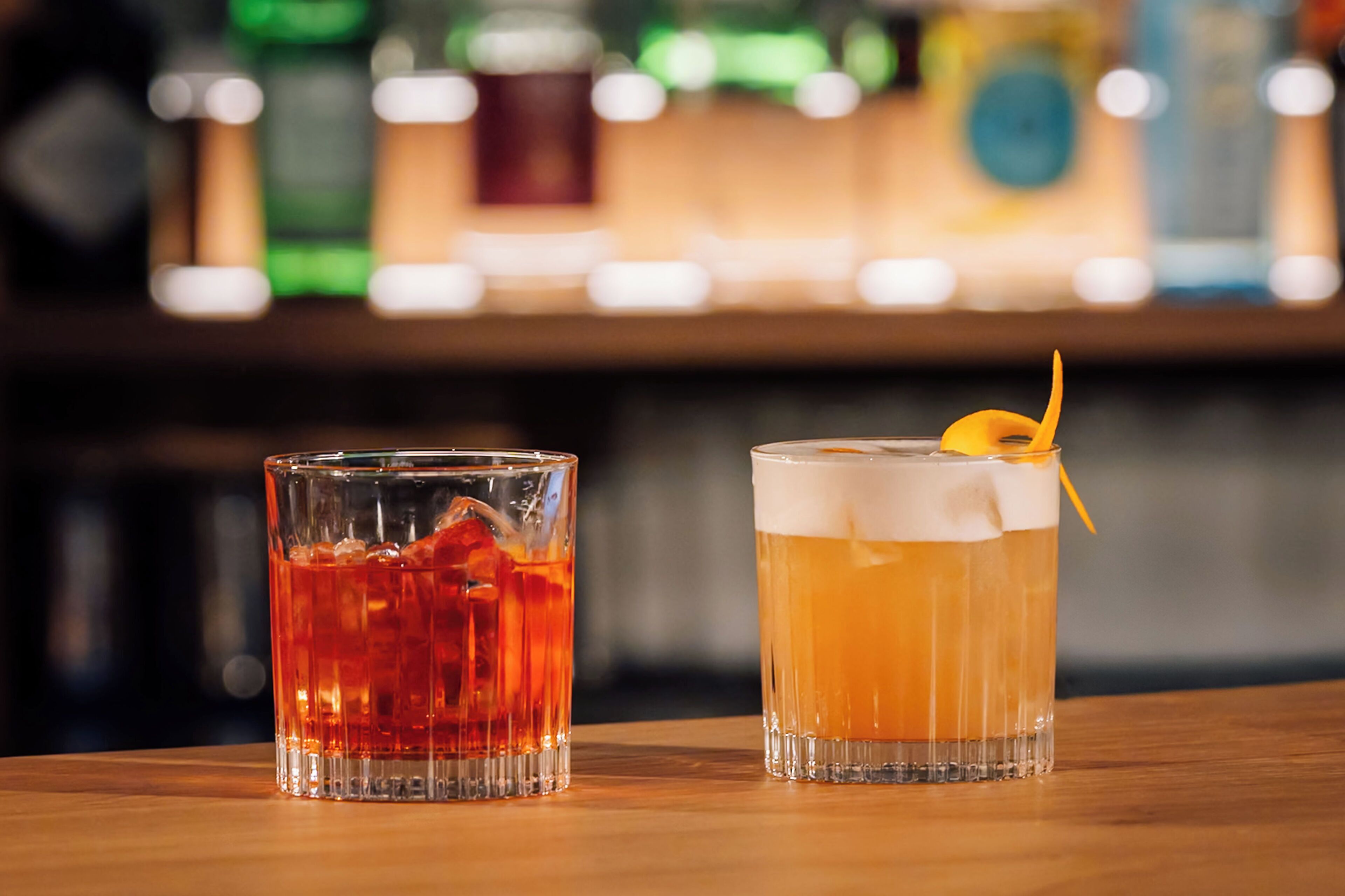 Dos vasos de bebidas sobre una superficie de madera, con un fondo desenfocado.