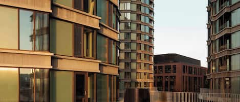A modern building with a curved facade, large windows, and a circular planter with plants.