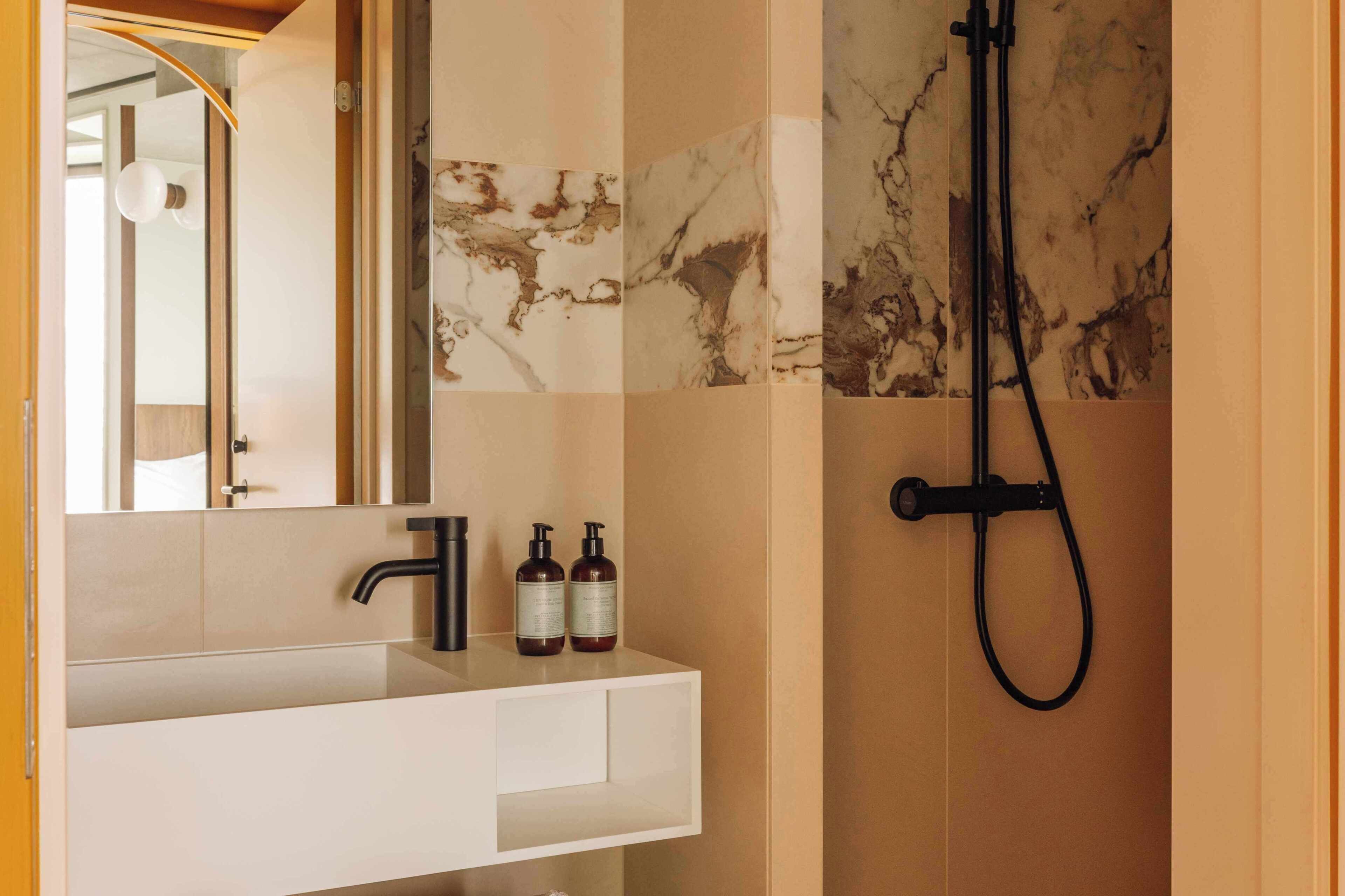 Une salle de bain avec un meuble-lavabo blanc, un robinet noir et deux bouteilles de shampoing.