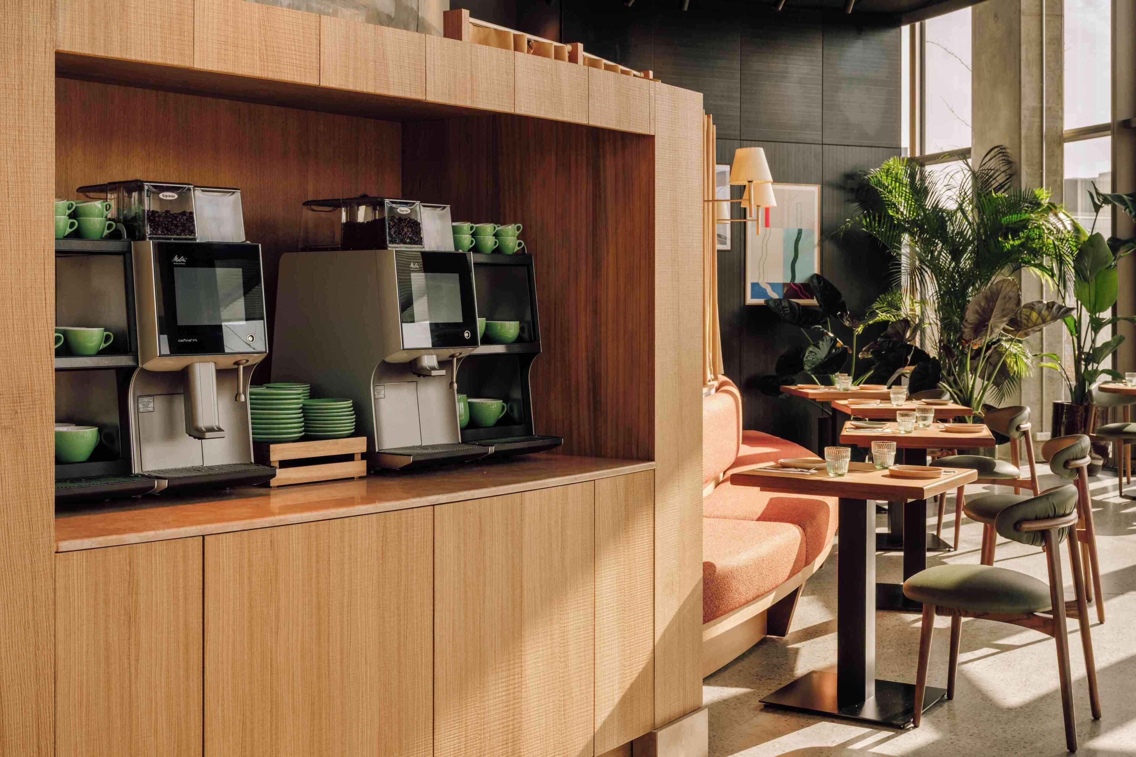 Un espace café moderne, équipé de machines à expresso et comprenant un coin salon avec des tables et des chaises.