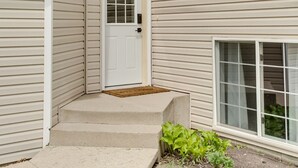 Une maison à deux étages avec une porte d’entrée, un petit porche et une fenêtre.