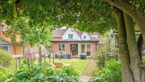 A garden with a pathway leading to a house with a patio area and a brick exterior.