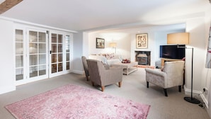 A living room with a fireplace, a television, and a large window.