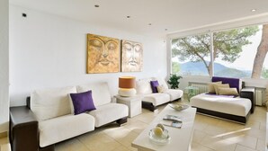 A modern living room with two white sofas, a coffee table, and artwork on the wall.