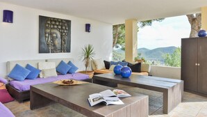 A modern living room with a sofa, coffee table, and a Buddha painting on the wall.