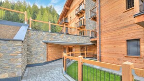 Un edificio in legno a più piani con balconi, pareti in pietra e un vialetto lastricato.