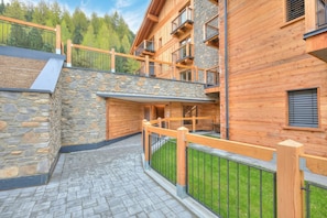 A multi-story wooden building with balconies, stone walls, and a paved walkway.
