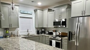 Una cucina moderna con ripiani in granito, elettrodomestici in acciaio inossidabile e mobili color grigio chiaro.