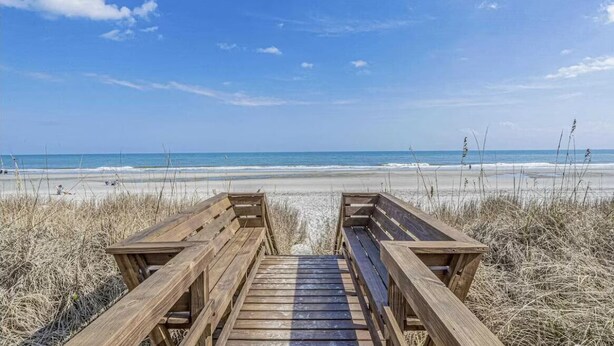 Una passerella di legno che conduce a una spiaggia, con vista libera sull'oceano.