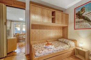 A bedroom with a bed, wooden wardrobe, and a poster on the wall.