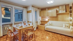 A room with a dining table, chairs, a sofa, and a radiator. - Appartamento Gran Roc few steps from Ski, Sestriere, Italy (Sestriere)