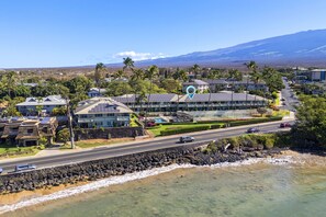 Un hotel frente al mar con vista al océano y una montaña al fondo.