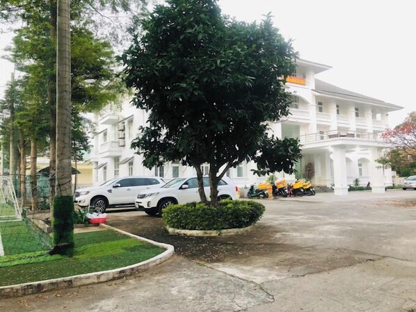 A large white building with a symmetrical facade, a central tree, and a paved driveway. - 683 Hotel DN - by Bay Luxury (Da Nang)