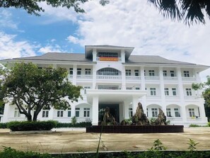 A large, multi-story building with a central entrance, surrounded by greenery and a clear sky. - 683 Hotel DN - by Bay Luxury (Da Nang)