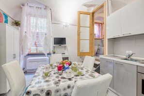 A compact kitchen with a dining area, a television, and a window with sheer curtains. - Oltremare, Sanremo, Italy (Sanremo)