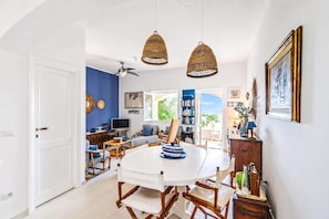 A dining area with a round table, chairs, and hanging wicker lamps.