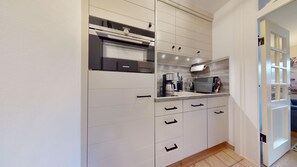 A modern kitchen with white cabinetry, a built-in oven, and a stainless steel range hood.