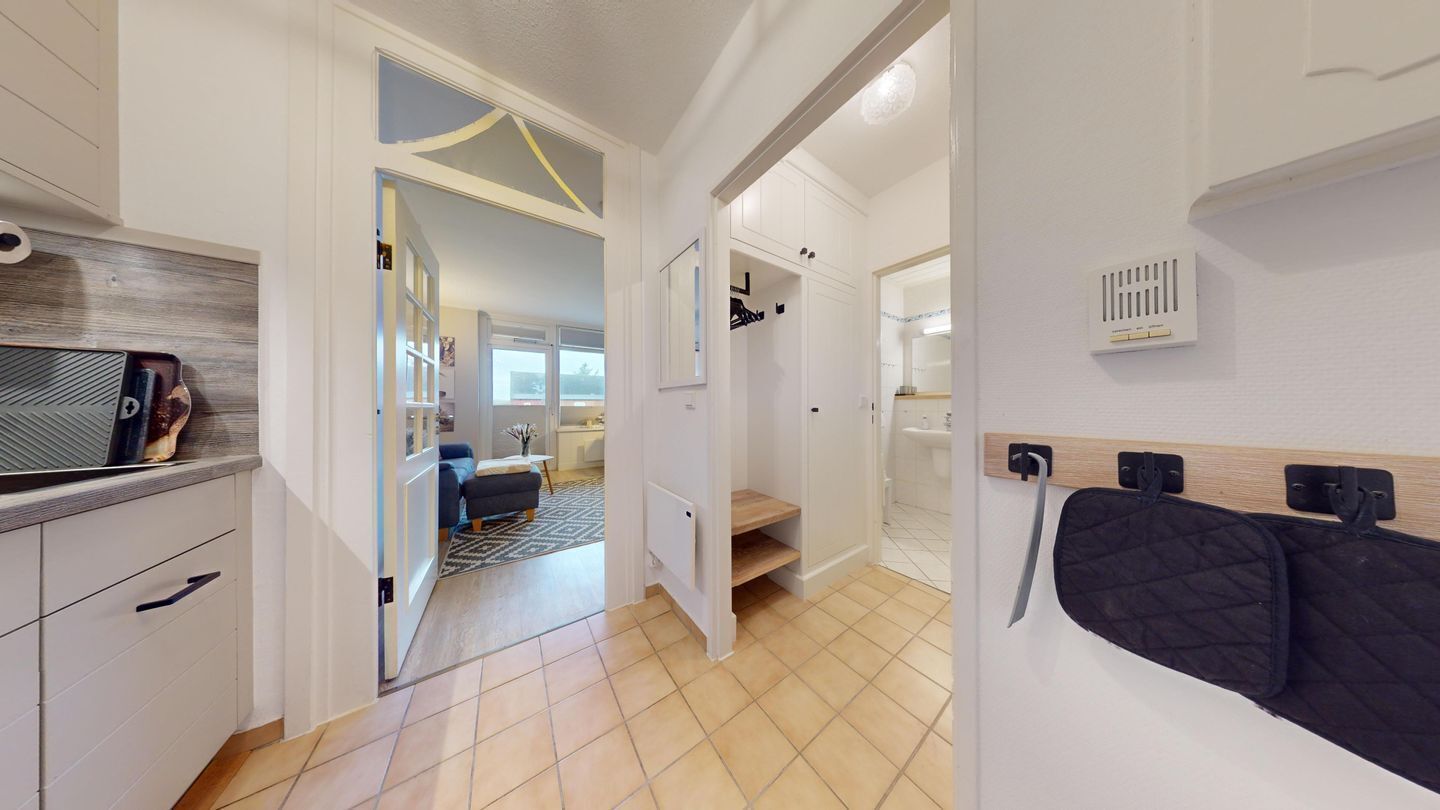 Un interno moderno con angolo cottura, zona pranzo e camera da letto con un letto e coperta trapuntata.