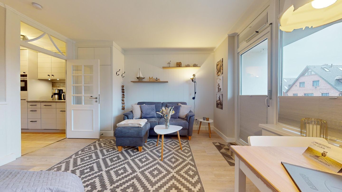 Una sala de estar moderna con un sofá, reposapiés, una mesa de centro y vistas al exterior.