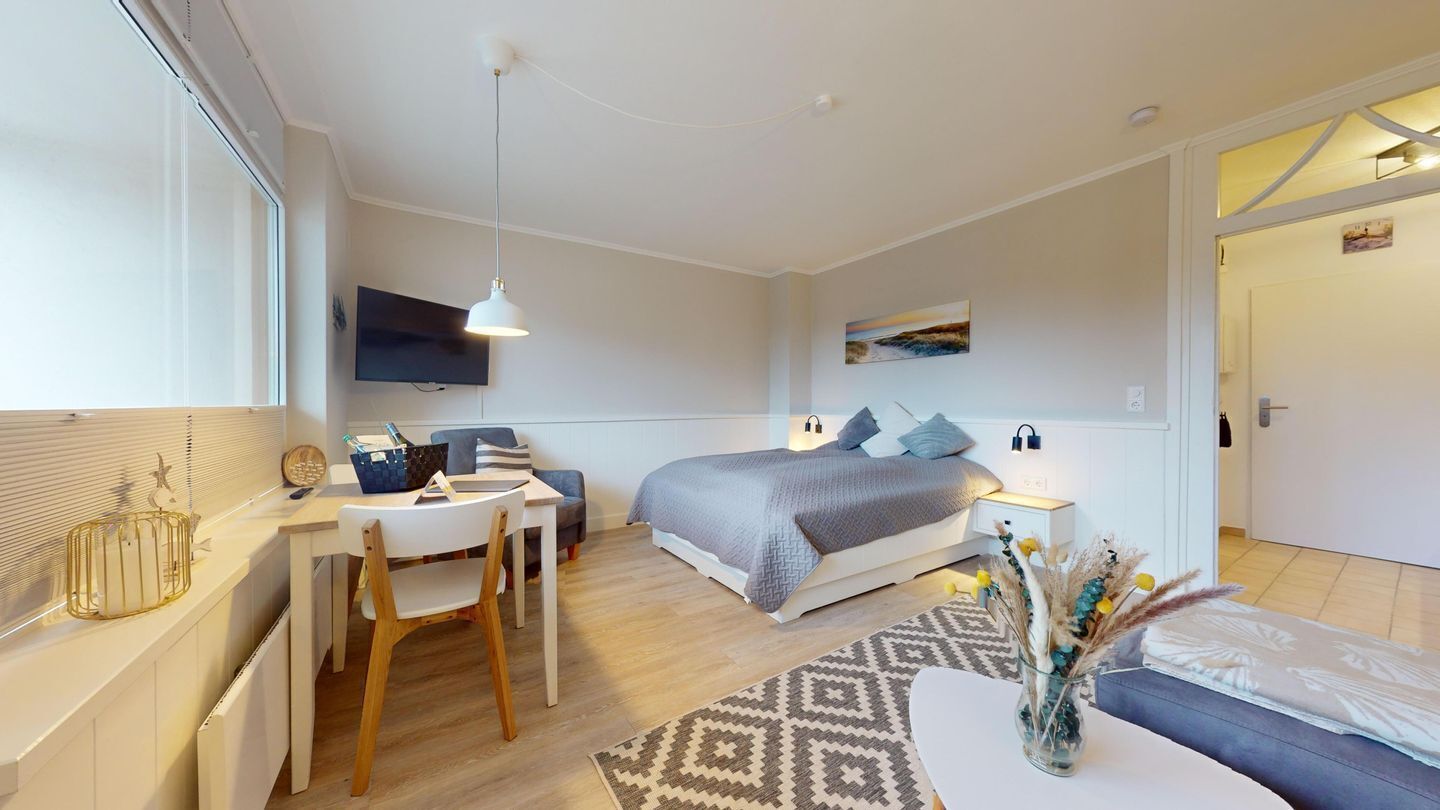 Un dormitorio moderno con una cama, una mesita de noche y un escritorio con una silla.