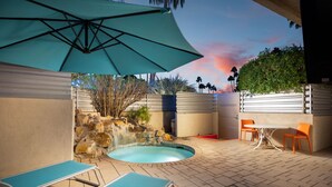 A pool area with lounge chairs, a table, and an umbrella.
