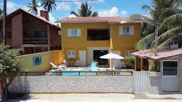 Un bâtiment à deux étages doté d’une piscine, de chaises longues et d’un patio couvert.