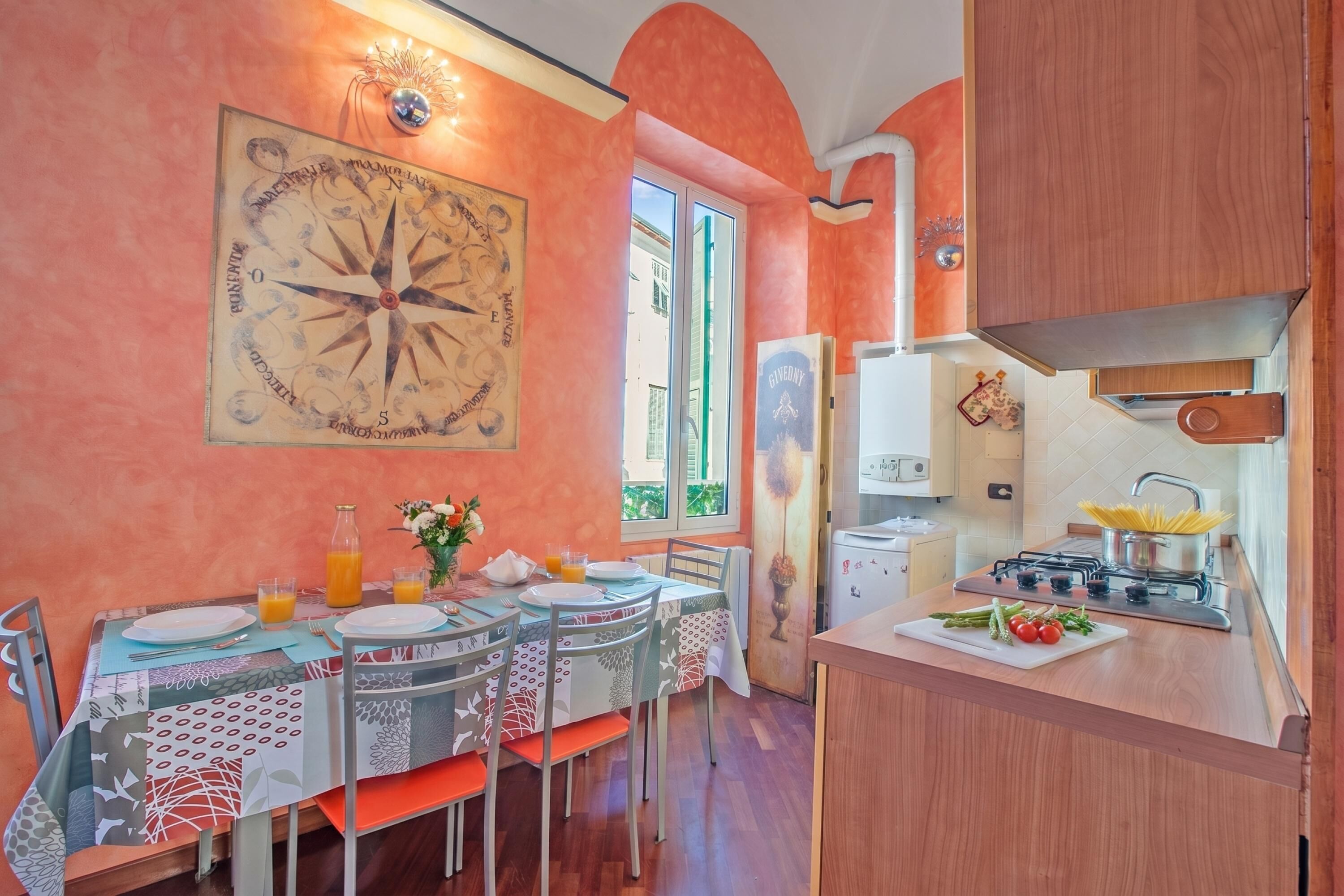 Un comedor con una mesa preparada para dos, una cocina con estufa y una gran decoración de brújula en la pared.