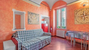 A room with a sofa, a dining table with chairs, a red refrigerator, and a large wall clock. - La Perla, Walk to Casino & Old Town, Sanremo, Italy (Sanremo)