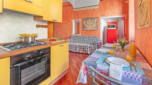 A kitchen with yellow cabinets, a stove, and a dining area with a table set for breakfast. - La Perla, Walk to Casino & Old Town, Sanremo, Italy (Sanremo)