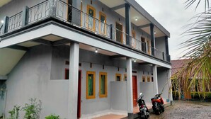 A multi-story building with a balcony, numbered doors, and two motorcycles parked outside. - Hotel Intan Niaga (Banjaran)
